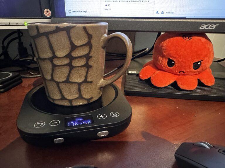 Coffee warmer with a mug of tea on it and an angry octopus plushie in the background